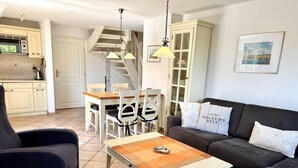 A living room with a sofa, armchair, and a coffee table. There is a staircase leading to an upper level. - Norderstraße, Apartment 3 - Cozy upper-floor vacation apartment with a south-facing balcony in (Sylt)
