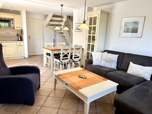A living room with a sofa, armchair, and a coffee table. There is a staircase leading to an upper level. - Norderstraße, Apartment 3 - Cozy upper-floor vacation apartment with a south-facing balcony in (Sylt)