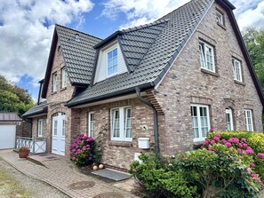 A two-story house with a brick facade, multiple windows, and a sloped roof. - Norderstraße, Apartment 3 - Cozy upper-floor vacation apartment with a south-facing balcony in (Sylt)