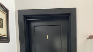 Una puerta negra con el número 1 en dorado y un picaporte.