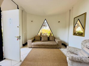 Una habitación con un sofá, un tapete estampado, una puerta y una ventana con vista a árboles.
