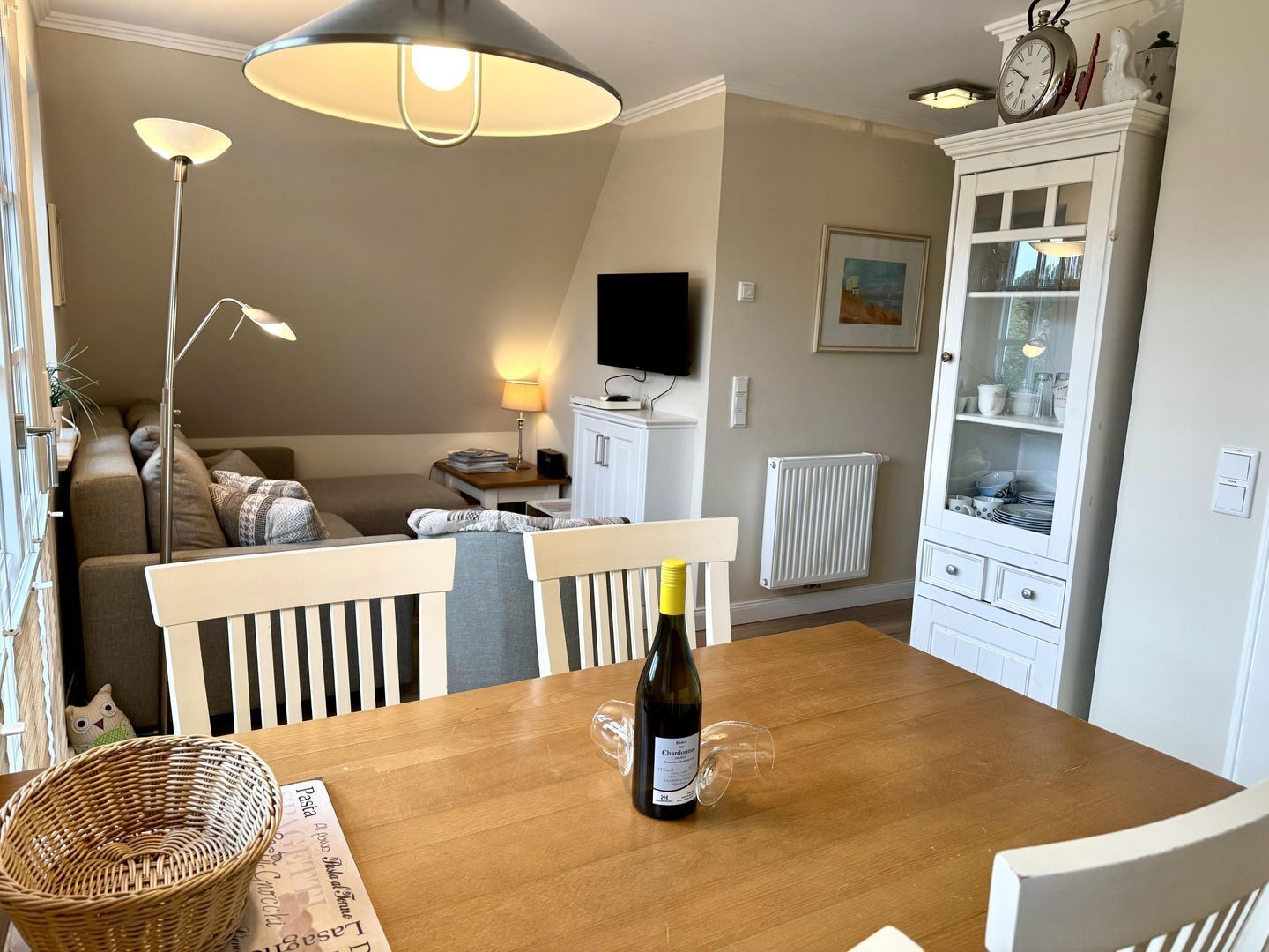Et spiseområde med et træbord, en vinflaske og en kurv.