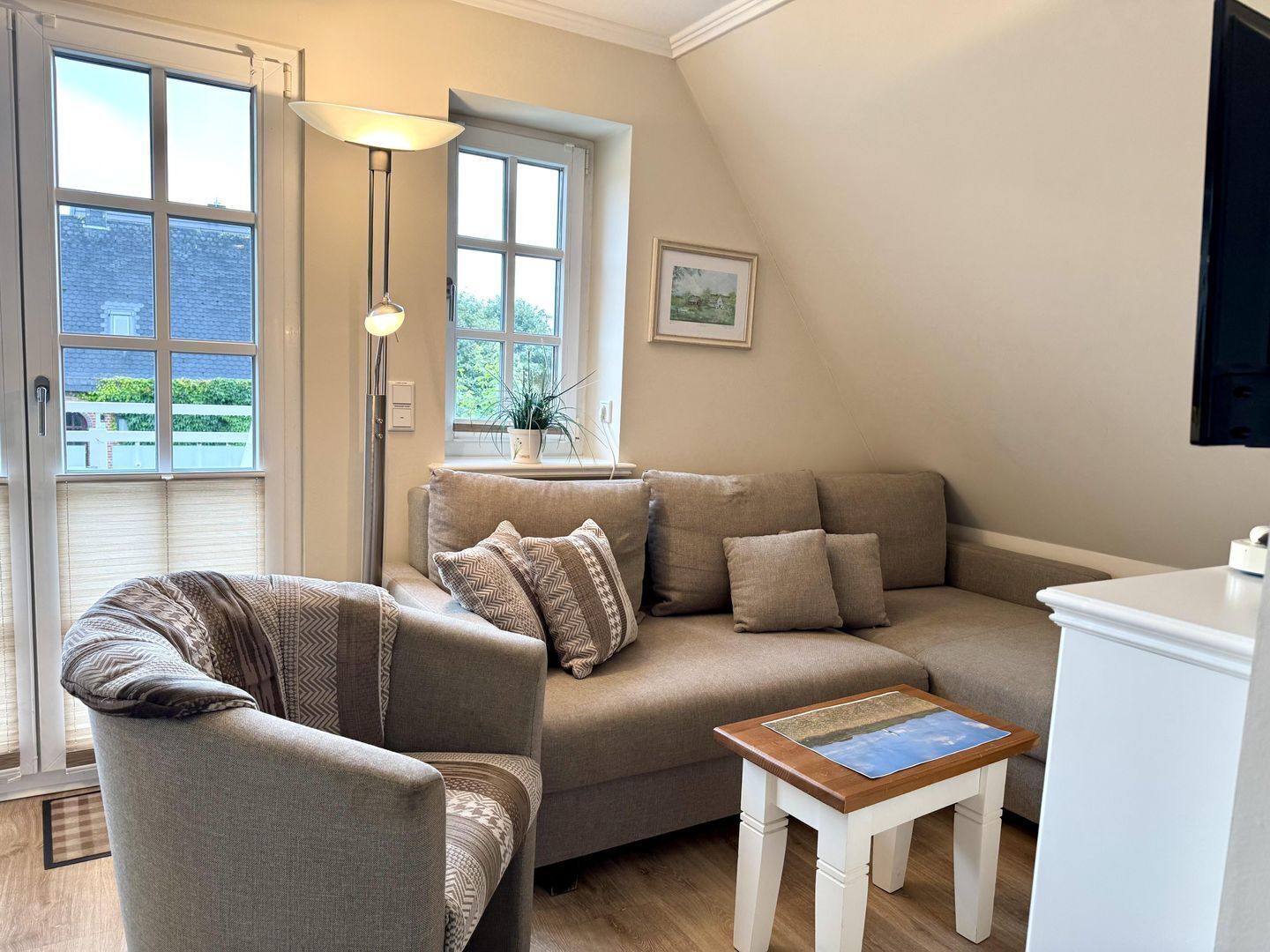 En hyggelig stue med en sofa, en lænestol og et lille bord med et billede.