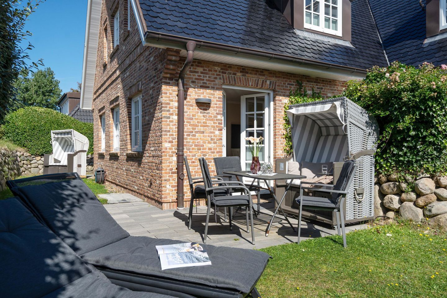 A brick house with a patio area featuring outdoor furniture and a grill.