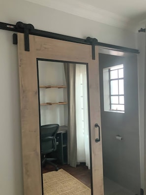 A room with a sliding door leading to a closet, a desk with a chair, and a window with a view.
