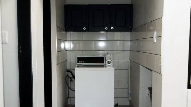 Una cocina compacta con un refrigerador blanco, un microondas y gabinetes oscuros.