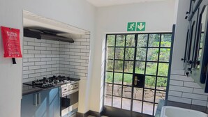 A kitchen with a gas stove, cabinets, a fire blanket, and a view through a door to an outdoor area. - Double Self-Contained Rooms 2 (Johannesburg)