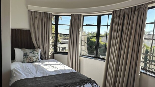 A bedroom with a bed, curtains, and a view of the outside. - Double Self-Contained Rooms 2 (Johannesburg)