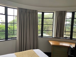 A hotel room with a bed, a desk, and large windows with curtains. - Double Self-Contained Rooms 2 (Johannesburg)