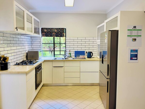 A kitchen with white cabinets, a gas stove, a sink, and a refrigerator.