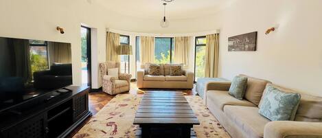 A living room with a TV, two sofas, a coffee table, and a chandelier.