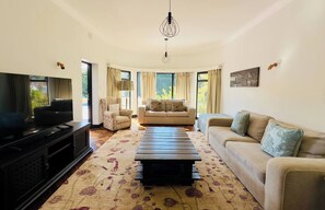A living room with a TV, two sofas, a coffee table, and a chandelier. - Double Self-Contained Rooms 4 (Johannesburg)