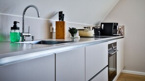 Et moderne køkken med en indbygget vask, kaffemaskine og et bestiksæt.