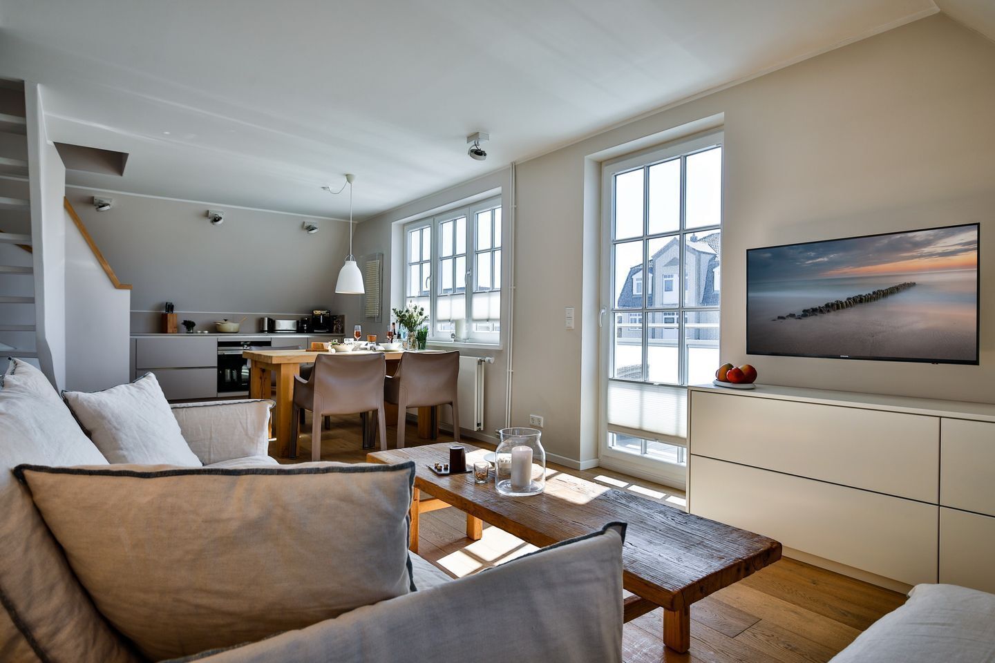 A modern living space with a dining area, kitchen, and a large window with a view.