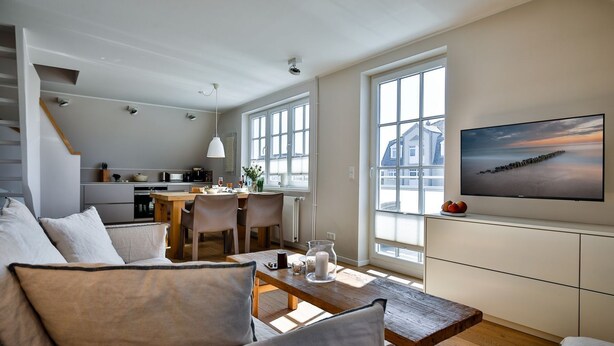 En moderne opholdsstue med spiseområde, køkken og et stort vindue med udsigt.