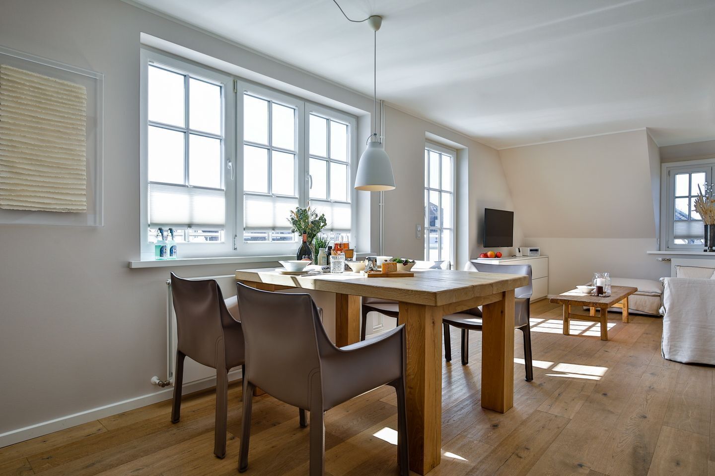 A modern kitchen with a dining table, chairs, and a TV.