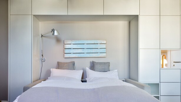 Un dormitorio moderno con cama, lámparas de noche y un aplique en la pared.