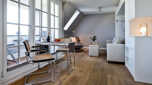 Un apartamento moderno estilo loft con zona de comedor, un sofá y una pequeña mesa con una botella y vasos.