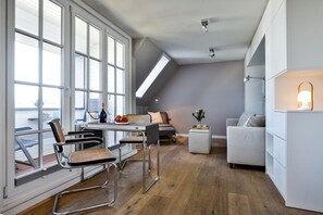Eine moderne Loft-Wohnung mit Essbereich, einer Couch und einem kleinen Tisch mit Flasche und Gläsern.