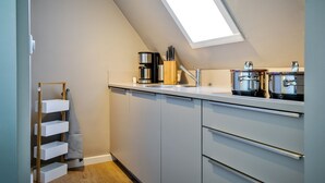 Una cocina moderna con tragaluz, armarios blancos y electrodomésticos de acero inoxidable.