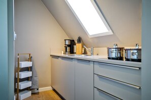 Eine moderne Küche mit Oberlichter, weißen Schränken und Edelstahlgeräten.