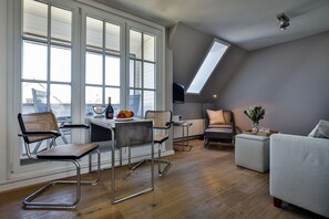 Ein modernes Loft-Apartment mit Essbereich, Sitzgelegenheiten und Blick durch große Fenster.