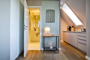 A modern kitchen with a skylight, a small table with a lamp, and a wall-mounted sign with beach rules. - House by the Sea, Strandküken - Your Cozy Strandküken Apartment in (Wenningstedt-Braderup (Sylt))