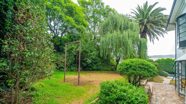 Un jardín con un columpio, un camino de piedra y un césped bien cuidado.