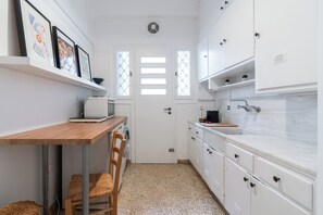 Eine kleine Küche mit weißen Schränken, einem Holztisch und einer Waschmaschine.