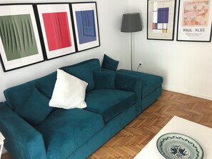 A teal sofa with a white pillow, a floor lamp, and framed artworks on the wall. - Elegant Pangrati Apartment Near Metro & Museums 
Entire apartment Up to 4 people (Athina)