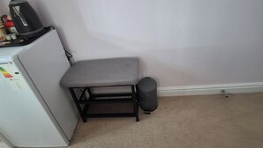 A small kitchenette with a refrigerator, a kettle, and a trash bin. - Charming Guest Room in West Midlands with Modern Amenities (West Midlands)