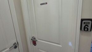 A white door with a 'No Smoking' sign, a doorbell, and a room number sign. - Charming Guest Room in West Midlands with Modern Amenities (West Midlands)