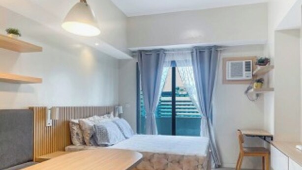 A bedroom with a bed, bedside table, and a window with curtains. - Cozy Retreat by Jane (Cebu City)