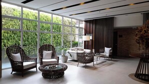 A modern living room with large windows, wicker furniture, and a view of greenery. - Cozy Retreat by Jane (Cebu City)