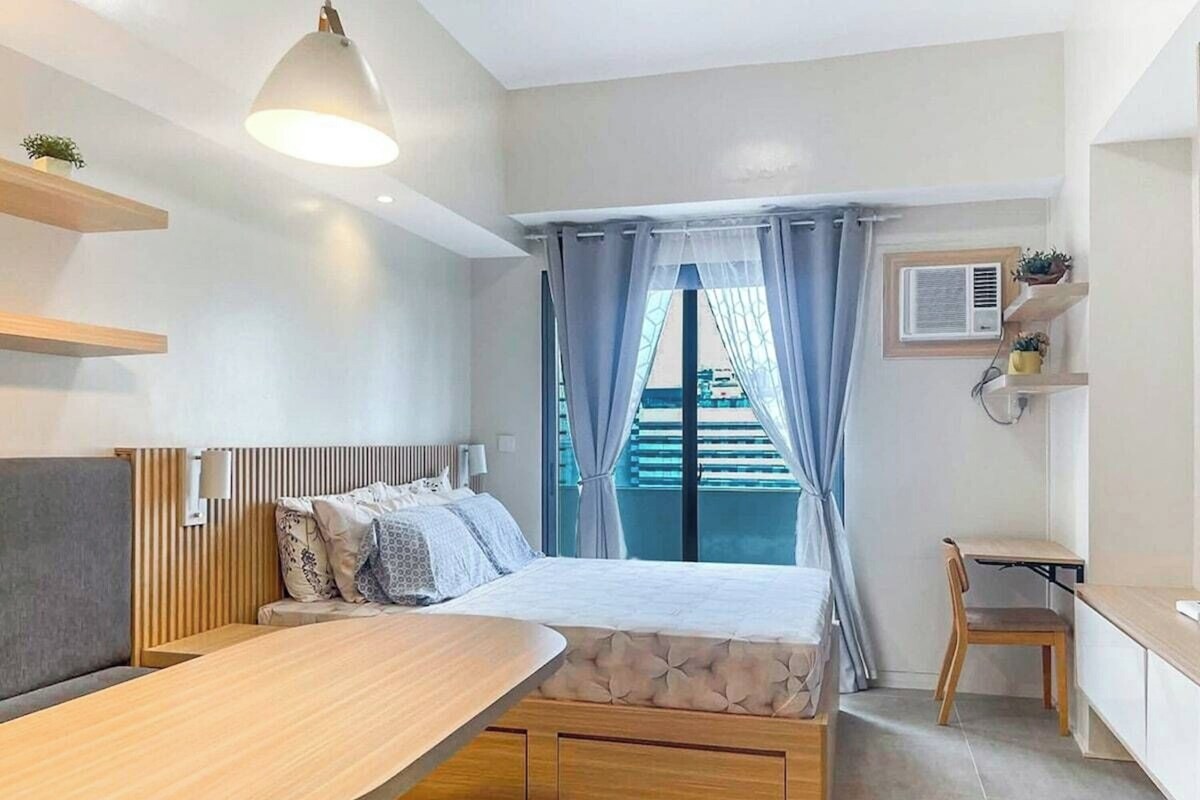 Ein modernes Schlafzimmer mit Bett, Nachttisch und Blick auf einen Balkon.