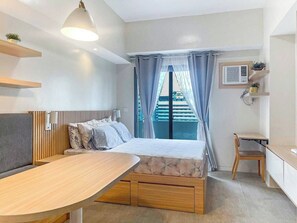 Ein modernes Schlafzimmer mit Bett, Nachttisch und Blick auf einen Balkon.