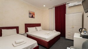 Habitación de hotel con dos camas, un escritorio, un armario y un televisor.