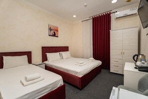 Habitación de hotel con dos camas, un escritorio, un armario y un televisor.