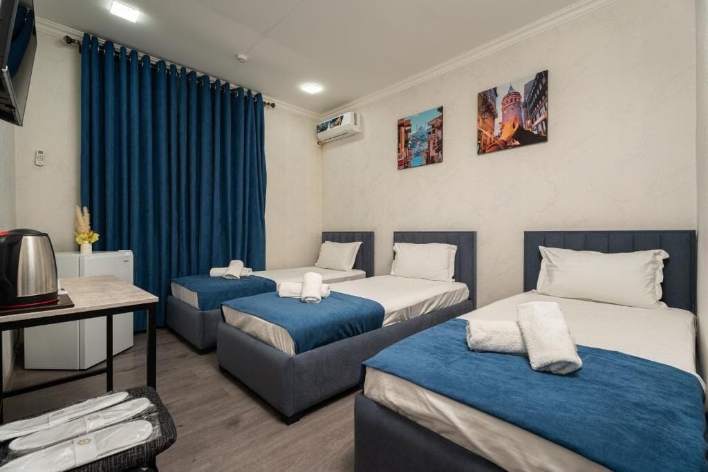 Habitación de hotel con dos camas, un escritorio con hervidor y una mesita con platos.