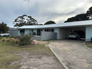 A single-story building with a garage, a covered outdoor area, and a gravel driveway. - Gulls Way, one of the best views in Paynesville (Paynesville)