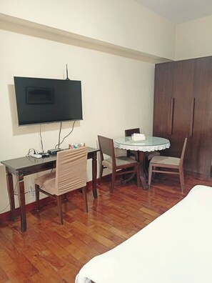 A room with a bed, a desk with a computer, a television, and a wardrobe. - 14M Lovely Studio Near Greenbelt (Makati)