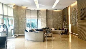 Een ruime lobby met een modern design, met een gebogen bank, een bijzettafeltje en een decoratief wandpaneel.