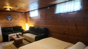 Une pièce de cabane en bois comprenant un lit, un canapé et une petite table avec une lampe.
