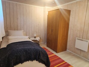 A bedroom with a bed, a nightstand, a wardrobe, and a radiator.