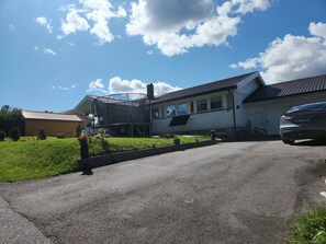 A residential property with a paved driveway, a covered outdoor area, and a garage.