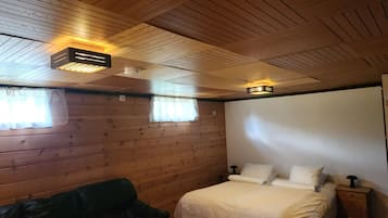 Ein Zimmer mit einem Bett, einer Holzbalkendecke und einem Fenster mit Vorhängen.
