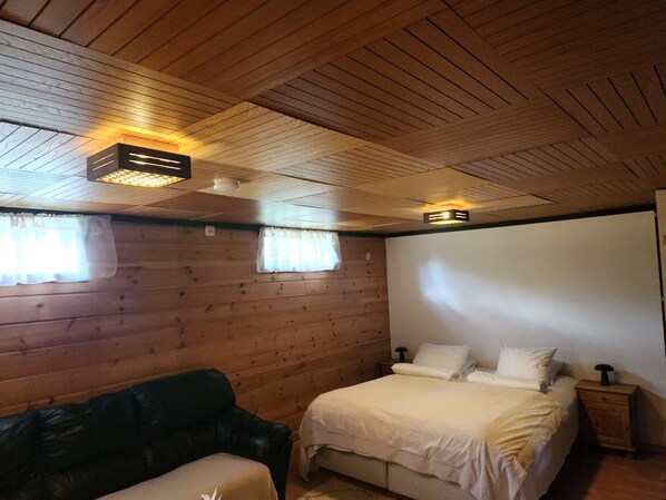 A room with a bed, a wooden ceiling, and a window with curtains.