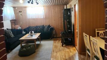 Ett mysigt vardagsrum med ett träpanelat tak, en soffa, ett soffbord och en matplats med stolar.