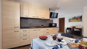 A modern kitchen with wooden cabinets, a microwave, and a dining area with a table set for breakfast.