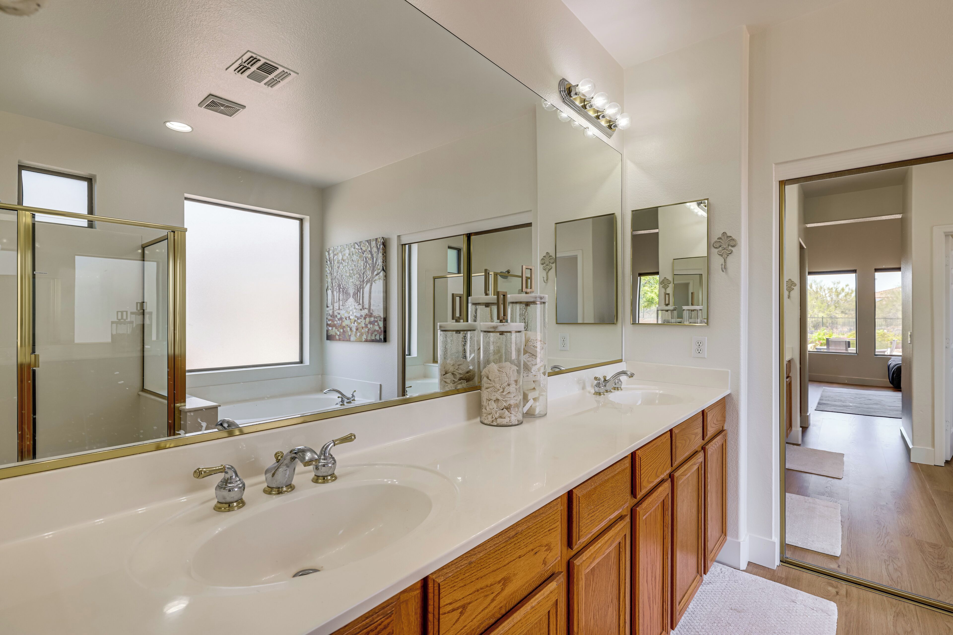 Une salle de bain avec un meuble-lavabo à deux vasques, des armoires en bois et un grand miroir.